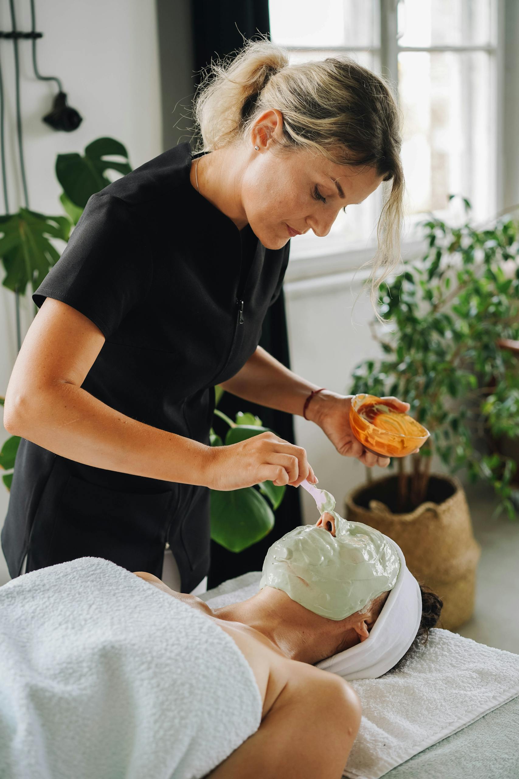 Aesthetician applying a soothing facial mask in a tranquil spa setting.